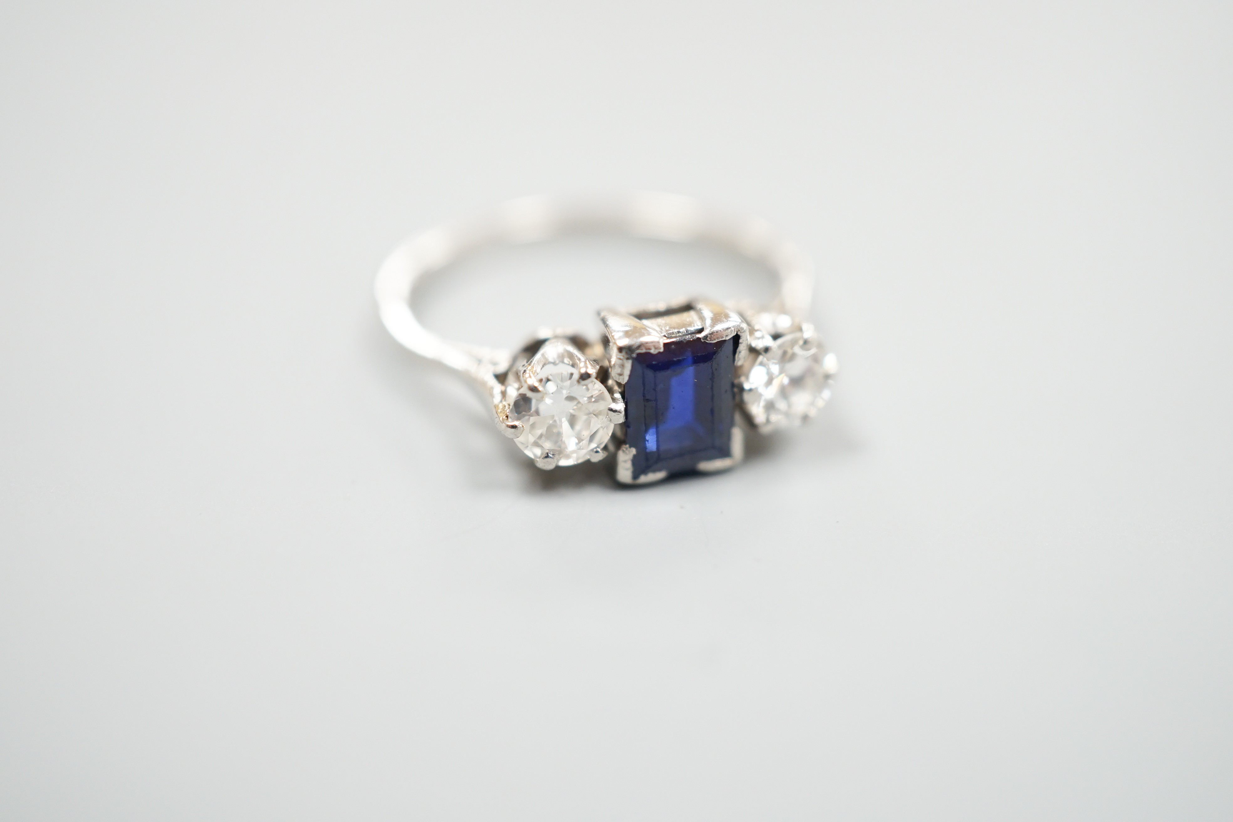 A white metal (stamped plat), sapphire and diamond set three stone ring, size K, gross weight 3.6 grams.